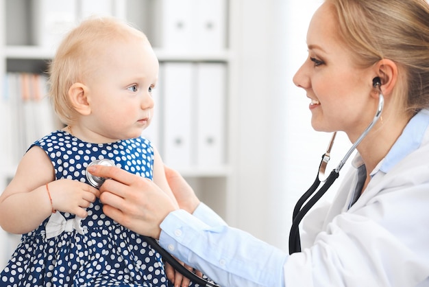 Médecin et patient à l'hôpital. Une petite fille vêtue d'une robe bleu foncé est examinée par un médecin avec un stéthoscope. Concept de médecine et de soins de santé.