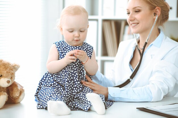 Médecin et patient à l'hôpital. Une petite fille vêtue d'une robe bleu foncé à pois est examinée par un médecin avec un stéthoscope. Notion de médecine.