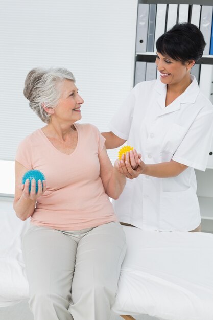 Médecin avec un patient senior en utilisant des boules de stress buster