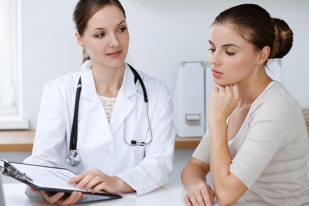 Photo le médecin et le patient sont assis et discutent des résultats de l'examen de santé au bureau de la clinique, de la médecine des soins de santé et des concepts de bonnes nouvelles