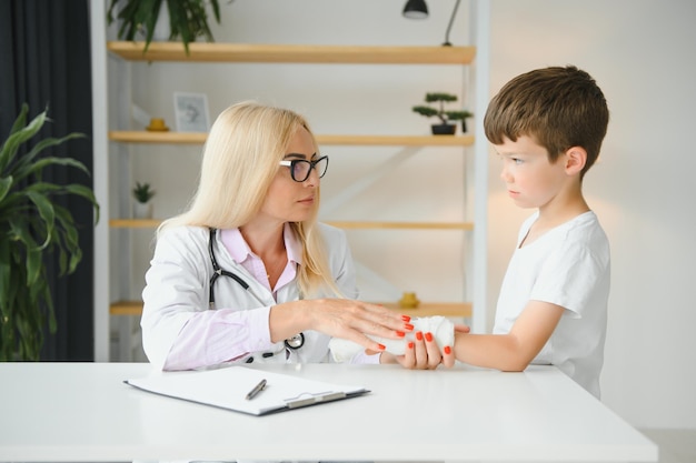 Médecin pédiatre bandant le bras de l'enfant Bras cassé chez un garçon