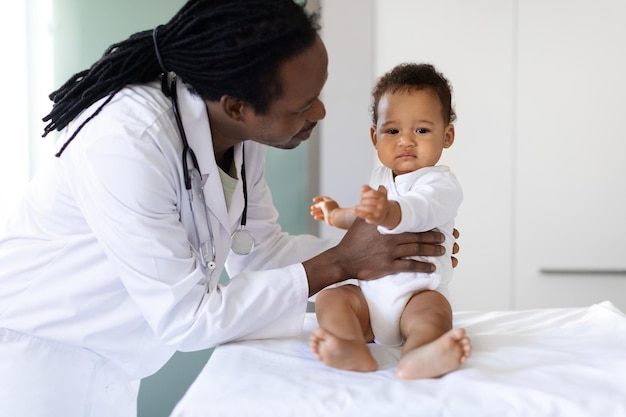 Photo médecin pédiatre souriant parlant à un bébé noir lors d'un rendez-vous à la clinique