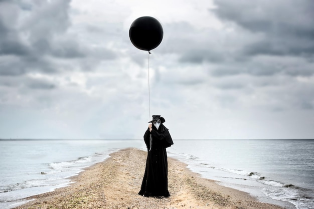 Médecin de la peste avec ballon noir en bord de mer Portrait en plein air avec ciel dramatique en arrière-plan