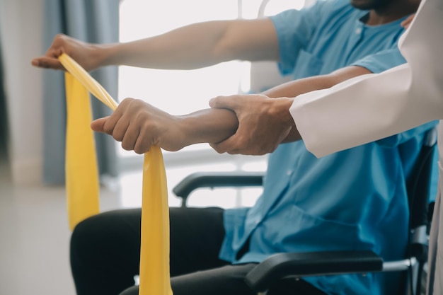 Photo médecin ou physiothérapeute travaillant à examiner le traitement du bras blessé d'un athlète homme patient étirement et exercice effectuer la thérapie de réadaptation de la douleur en clinique