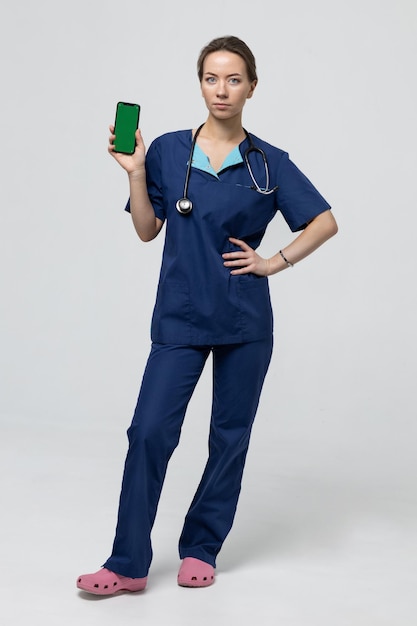 Un médecin de pleine longueur dans un costume bleu sur fond blanc Clé Chroma sur le téléphone annonçant la nouvelle clinique