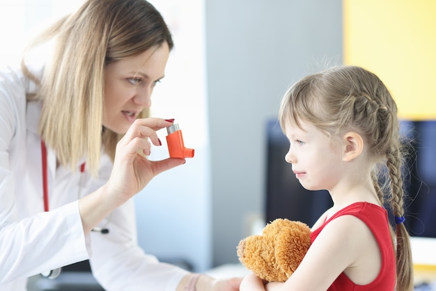 Médecin pneumologue tenant un inhalateur hormonal en face de la petite fille traitement des bronches