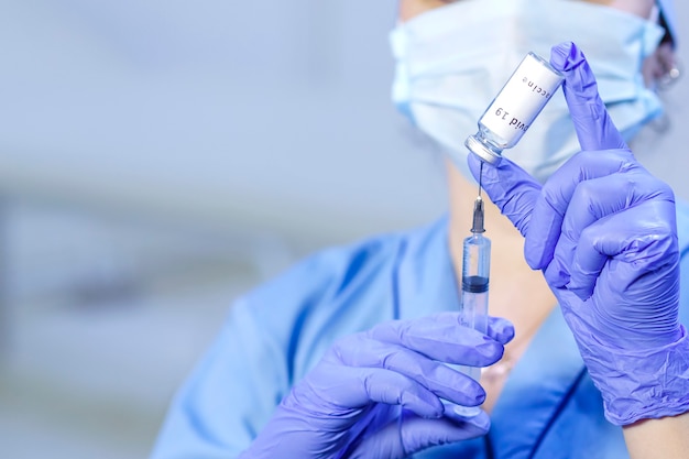 Un médecin portant des gants médicaux et un masque tient un flacon avec un vaccin et une seringue. photo horizontale