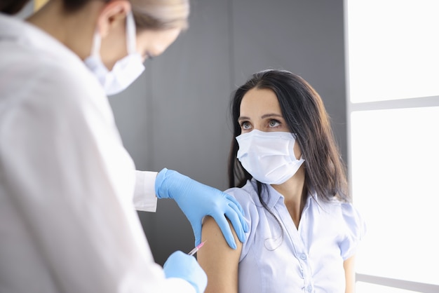 Photo un médecin portant un masque médical injecte un patient dans la vaccination de l'épaule de la population contre