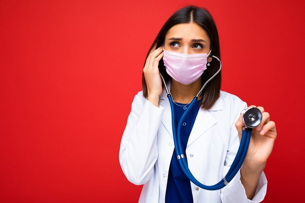 Médecin portant un masque médical et un stéthoscope isolé sur fond.