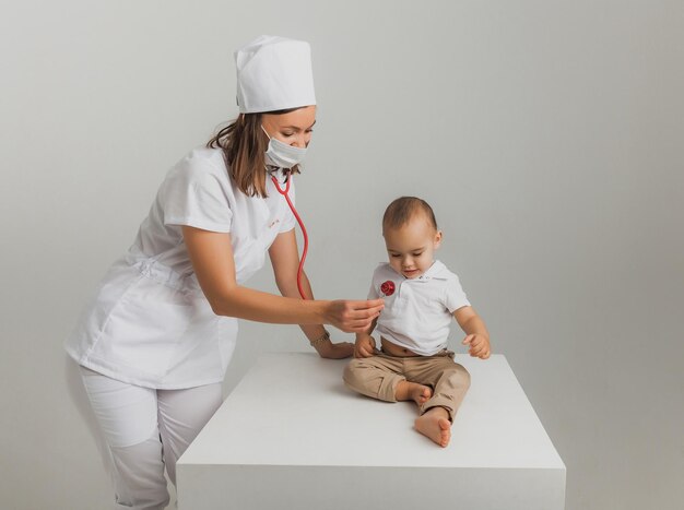 Un médecin pour enfants examine un garçon d'un an avec un stéthoscope dans un centre hospitalier. notion de santé