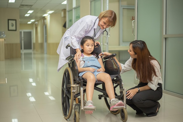 Un médecin pousse une jeune patiente dans le couloir de l'hôpital avec sa mère