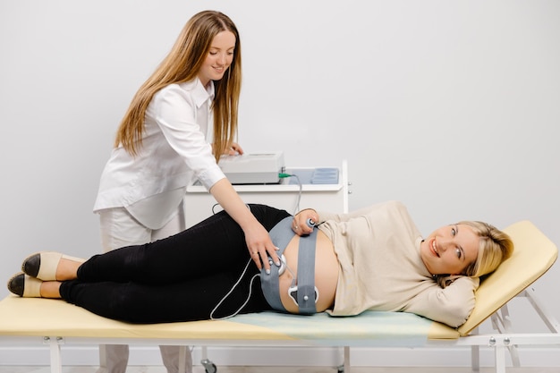 Un médecin prépare une femme enceinte à vérifier le rythme cardiaque fœtal par surveillance fœtale