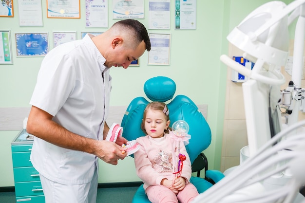 Médecin professionnel, dentiste pédiatrique apprend à un enfant à se brosser les dents. Cabinet dentaire pour l'examen des patients. Le processus de traitement dentaire chez un enfant.