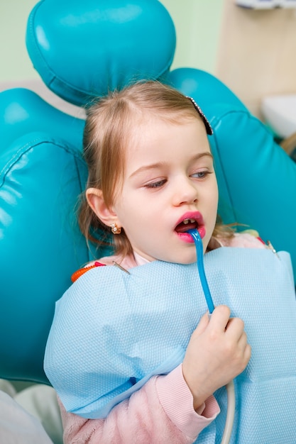 Un médecin professionnel, un dentiste pour enfants, soigne les dents d'une petite fille avec des instruments. Cabinet dentaire pour l'examen des patients. Le processus de traitement dentaire chez un enfant