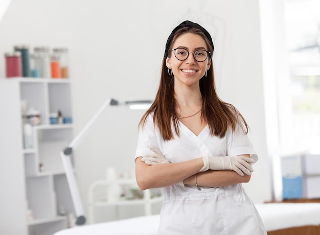 Médecin professionnel réussi cosmétologue dermatologue femme en vêtements médicaux blancs dans son salon de beauté souriant