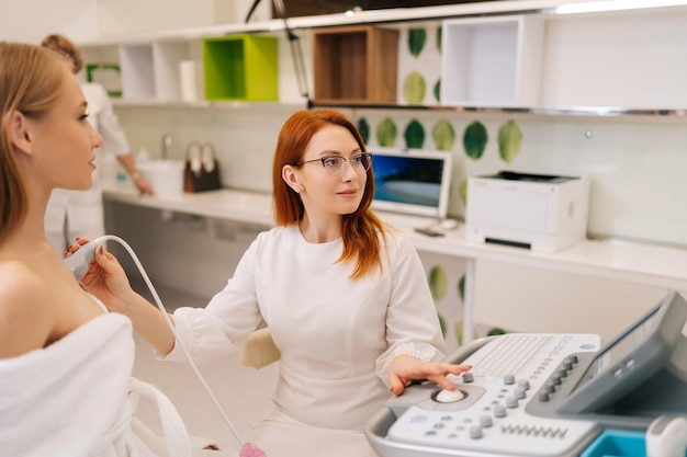 Une médecin professionnelle effectuant un examen par ultrasons du sein d'une jeune femme non reconnaissable