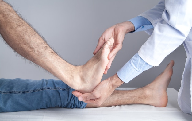 Médecin de race blanche examinant le pied du patient.