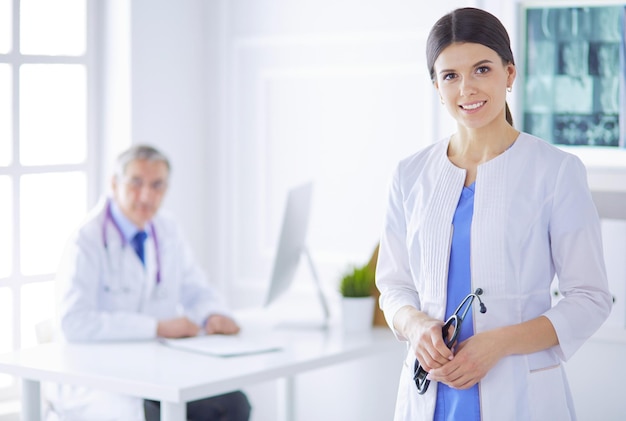 Un médecin regardant la caméra avec son collègue masculin à l'arrière de la salle de conférence à l'hôpital