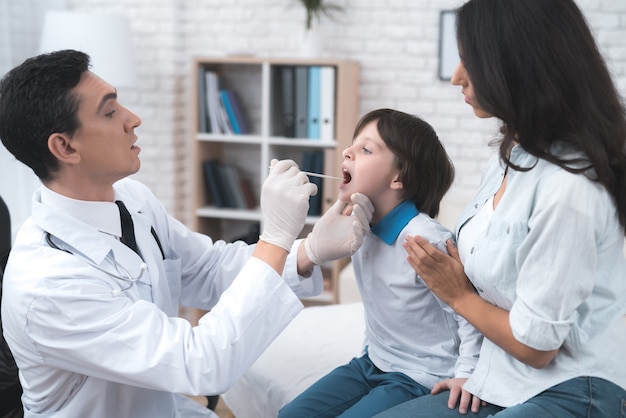 Le médecin regarde la gorge du garçon.