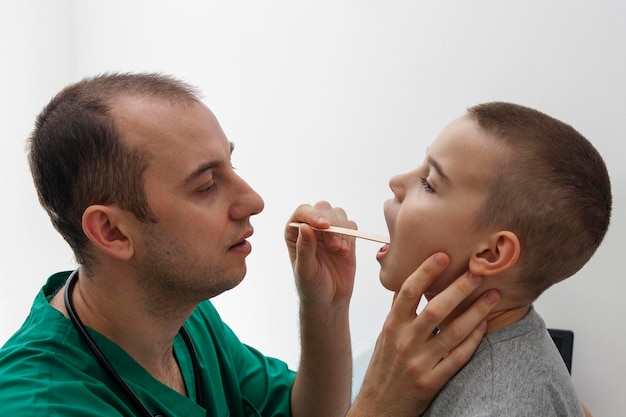 Le médecin regarde la gorge d'un enfant. Maladies et traitement des organes respiratoires, diagnostic. Notion médicale.