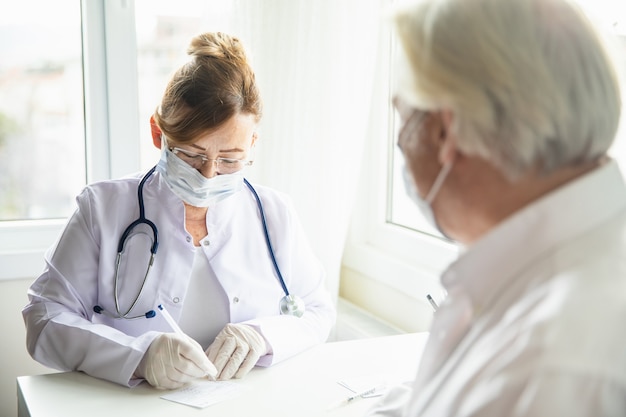 Le médecin remplit la carte de vaccination contre le coronavirus pour un patient âgé pendant la pandémie de Covid-19. Le concept de vaincre Covid-19