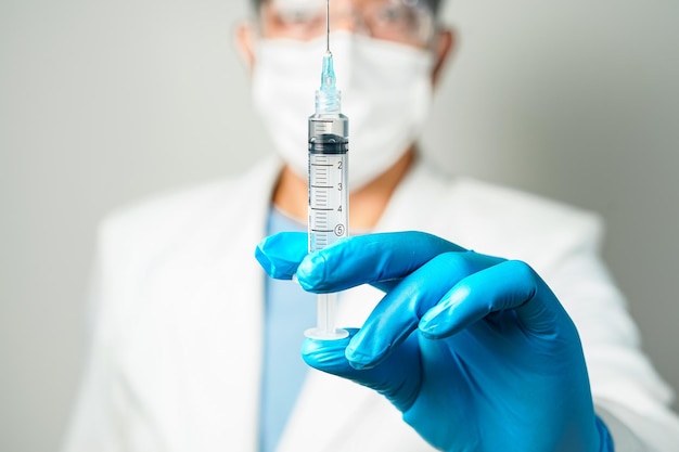 médecin ou scientifique tenant une seringue dans des gants bleus