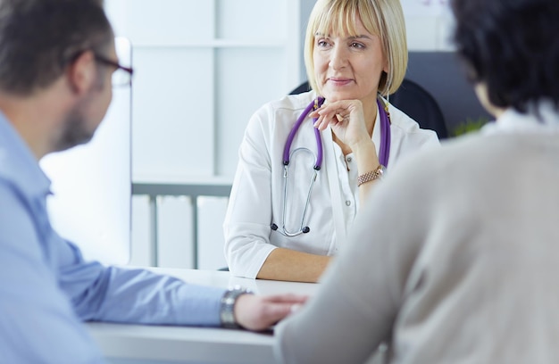 Médecin senior attentif à l'écoute du patient dans son bureau