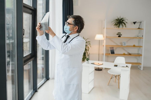 Un médecin senior regardant la radiographie dans son bureau