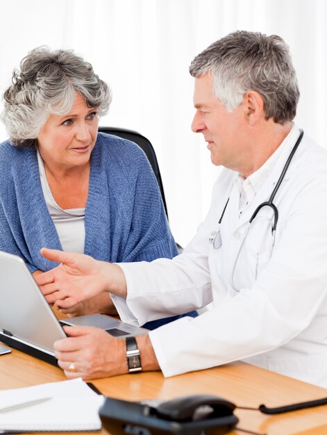 Photo un médecin senior avec son patient en regardant l'ordinateur portable