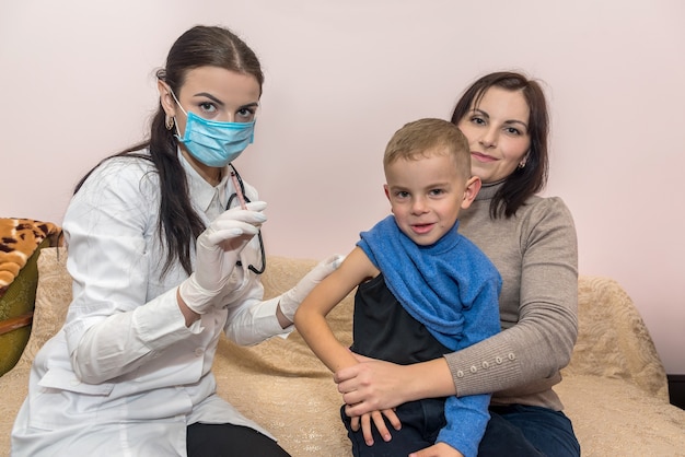 Médecin avec seringue et garçon assis sur les genoux de la mère