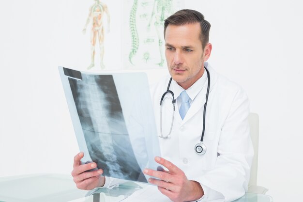 Médecin de sexe masculin concentré en regardant la photo de radiographie