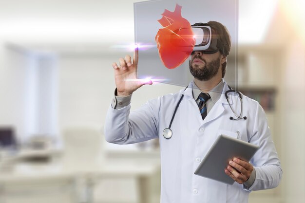 Médecin de sexe masculin dans son bureau, à l'aide de lunettes de réalité virtuelle, regardant un cœur virtuel