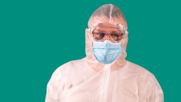 Médecin de sexe masculin avec un écran facial en uniforme de combinaison EPI portant un masque de protection médicale