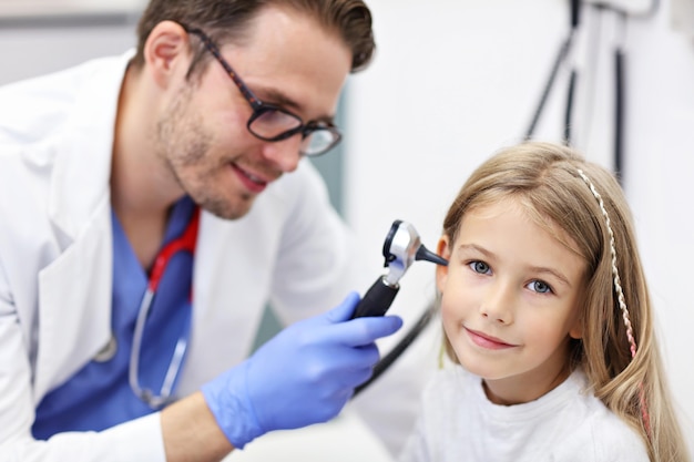 Médecin de sexe masculin examinant l'oreille de la fille avec un otoscope