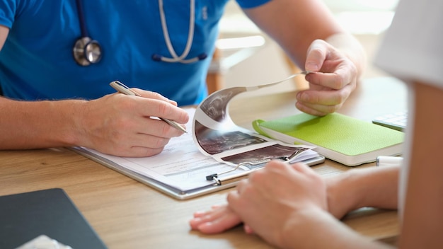 Photo un médecin de sexe masculin examine le résultat du test échographique d'une patiente assise à l'hôpital