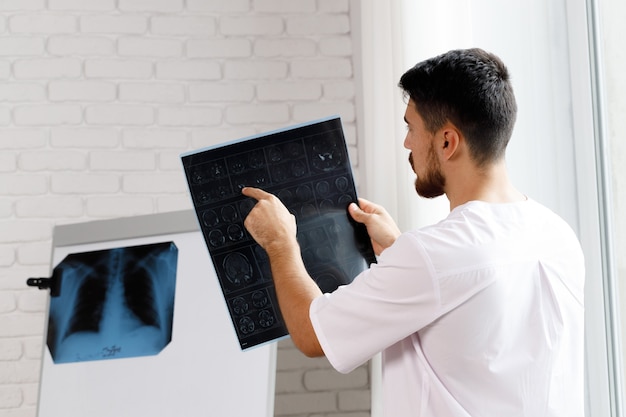 Médecin de sexe masculin examine le scanner cérébral IRM d'un patient