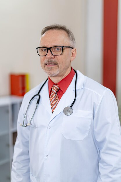 Médecin de sexe masculin en gommage avec un stéthoscope autour du cou et les bras dans les poches. Vue verticale dans un établissement médical moderne.