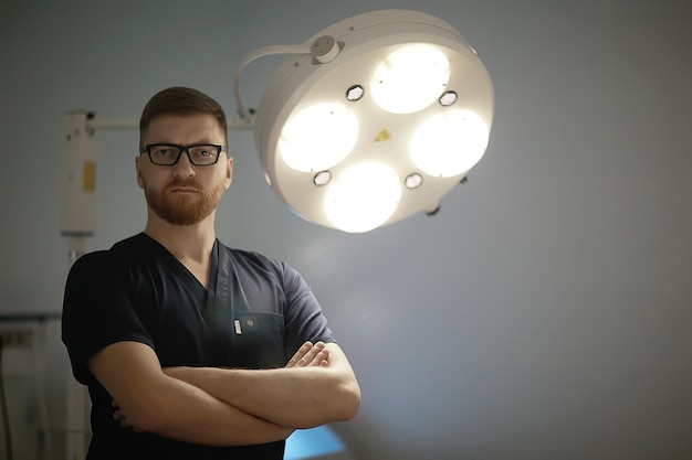 médecin de sexe masculin / jeune homme en uniforme médian, médecin strict avec des lunettes, clinique médicale