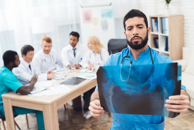 Médecin de sexe masculin en manteau bleu montre des rayons x.