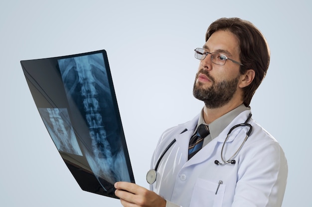 Médecin de sexe masculin sur un mur gris à la recherche d'une radiographie