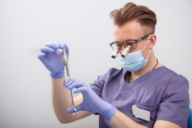 Médecin de sexe masculin portant des lunettes de microscope, préparant la seringue pour l'injection