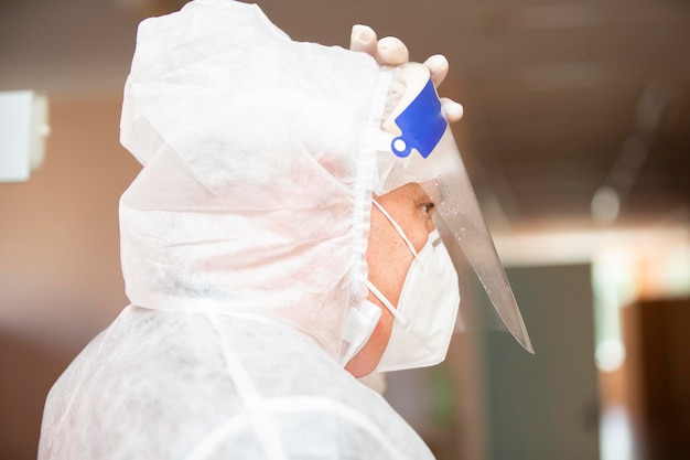 Médecin de sexe masculin portant un masque de protection et une combinaison de profil pour l'infection à coronavirus