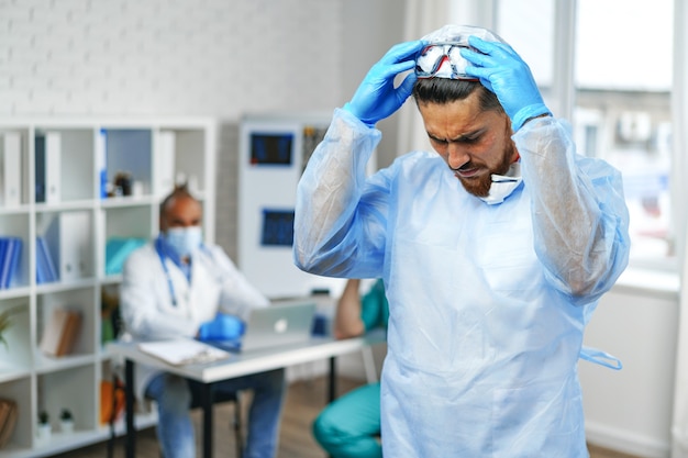 Médecin de sexe masculin en robe médicale de protection debout dans l'armoire de l'hôpital