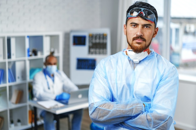 Médecin de sexe masculin en robe médicale de protection debout dans le cabinet de l'hôpital, portrait