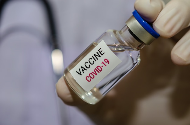 Médecin de sexe masculin tenant une bouteille de vaccin contre le COVID-19 ou le vaccin contre le coronavirus