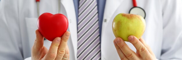 Médecin de sexe masculin tenant gros plan coeur et pomme rouge