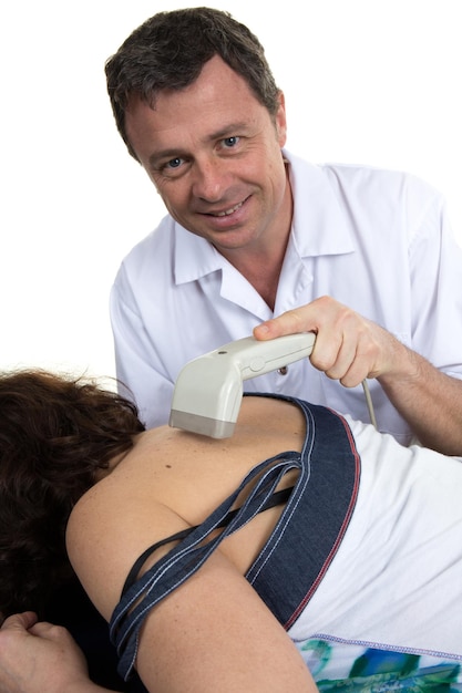 Médecin souriant à l'aide d'un appareil à ultrasons sur le dos de la femme