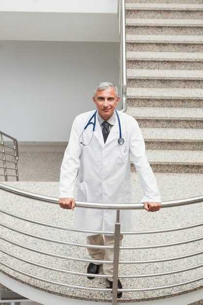 Médecin souriant appuyé sur la balustrade de l&#39;escalier