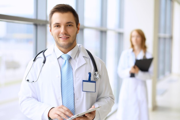 Médecin souriant attendant son équipe en se tenant debout