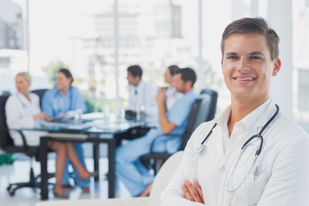 Médecin souriant avec les bras pliés debout